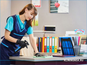 Девушка клинер протирает пыль на рабочем столе